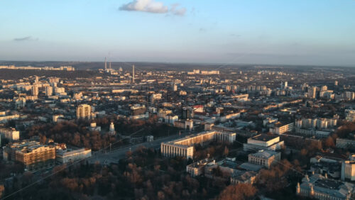 Video - Aerial drone view of Chisinau at sunset. Panorama view of multiple buildings, roads with moving cars, bare trees. Moldova