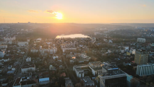 Video - Aerial drone view of Chisinau at sunset. Panorama view of multiple residential buildings, bare trees, park with lake. Moldova