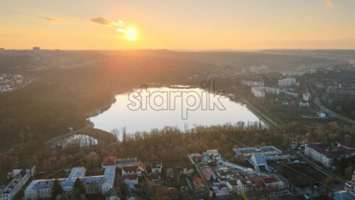 Video - Aerial drone view of Chisinau at sunset. Panorama view of multiple residential buildings, bare trees, park with lake. Moldova