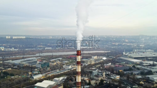 Video - Aerial drone view of Chisinau. Tube of the thermal station with smoke coming out. Cityscape on the background. Cloudy weather. Moldova