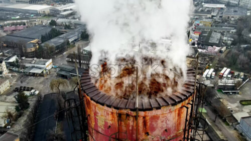 Video - Aerial drone view of Chisinau. Tube of the thermal station with smoke coming out. Cityscape on the background. Cloudy weather. Moldova