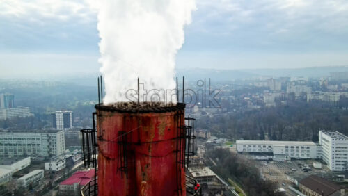 Video - Aerial drone view of Chisinau. Tube of the thermal station with smoke coming out. Cityscape on the background. Cloudy weather. Moldova