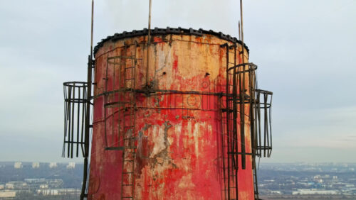 Video - Aerial drone view of Chisinau. Tube of the thermal station with smoke coming out. Industrial zone near it and cityscape on the background. Cloudy weather. Moldova