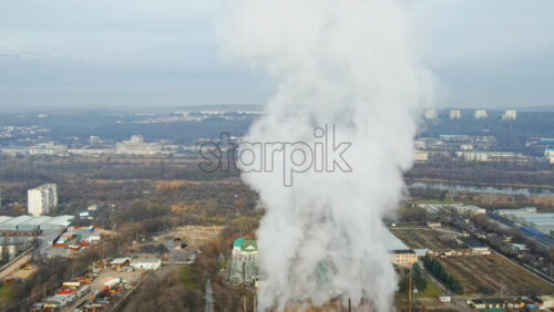 Video - Aerial drone view of Chisinau. Tube of the thermal station with smoke coming out. Industrial zone near it and cityscape on the background. Cloudy weather. Moldova