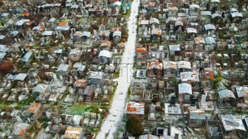 Video - Aerial drone view of a cemetery in Chisinau, Moldova. Multiple graves, crypts, walkway, Cloudy weather, bare trees, winter