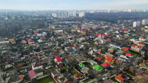 Video - Aerial drone view of a residential distict in Chisinau, Moldova. Multiple buildings, road, moving cars, Cloudy weather, bare trees, winter
