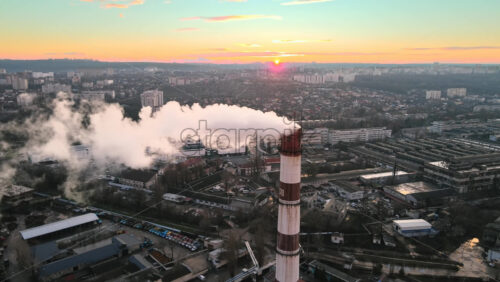 Video - Aerial drone view of Chisinau at sunset. Tube of the thermal station with smoke coming out. Industrial zone near it and cityscape on the background. Moldova