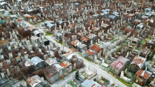 Video - Aerial drone view of a cemetery in Chisinau, Moldova. Multiple graves, crypts, walkway, Cloudy weather, bare trees, winter