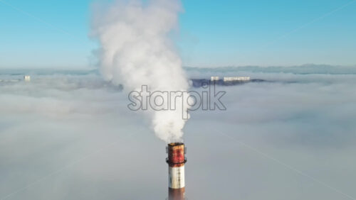 Video - Aerial drone view of Chisinau. Tube of the thermal station with smoke coming out above the low clouds. Visible buildings. Moldova
