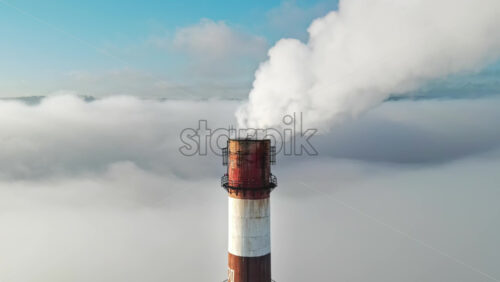 Video - Aerial drone view of Chisinau. Tube of the thermal station with smoke coming out above the low clouds. Visible buildings. Moldova