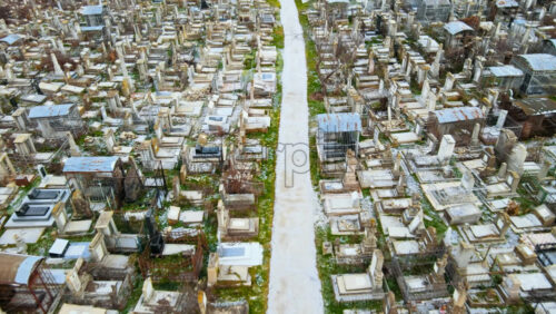 Video - Aerial drone view of a cemetery in Chisinau, Moldova. Multiple graves, crypts, walkway, Cloudy weather, bare trees, winter