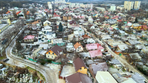 Video - Aerial drone view of a residential distict in Chisinau, Moldova. Multiple buildings, road, cemetery on the left, Cloudy weather, bare trees, winter