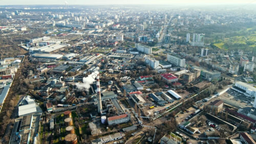 Video - Aerial drone view of Chisinau. Panorama view of multiple buildings, thermal station, roads with moving cars and bare trees. Good weather with fog in the air. Moldova