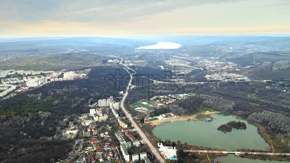 Video - Aerial drone view of Chisinau and suburban lands. Panorama view of buildings, road, hills covered with bare trees, two lakes, one in the distance. Good weather. Moldova