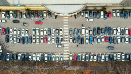 Video - Aerial drone view of Chisinau. View of a parking near a mall, road with moving cars, walking people and bare treest. Moldova