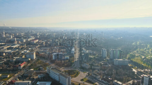 Video - Aerial drone view of Chisinau. Panorama view of multiple buildings, roads with moving cars and bare trees. Good weather with fog in the air. Moldova