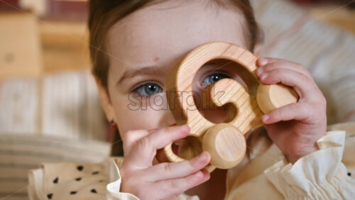 Video - Little girl with blue eyes holding a wooden snail rolling toy. Ecological and sustainability concept