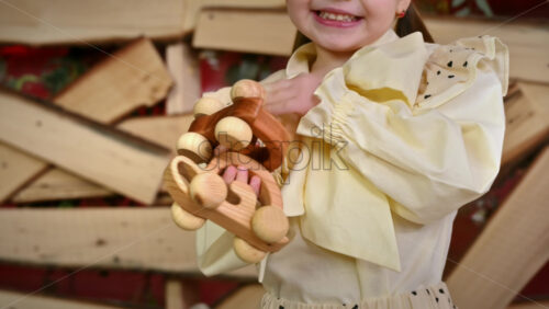 Video - Little girl with blue eyes holding two wooden snail rolling toys and smiles. Ecological and sustainability concept