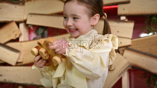 Video - Little girl with blue eyes holding two wooden snail rolling toys and smiles. Ecological and sustainability concept