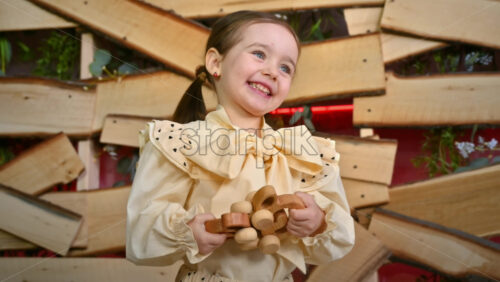 Video - Little girl with blue eyes holding two wooden snail rolling toys and smiles. Ecological and sustainability concept