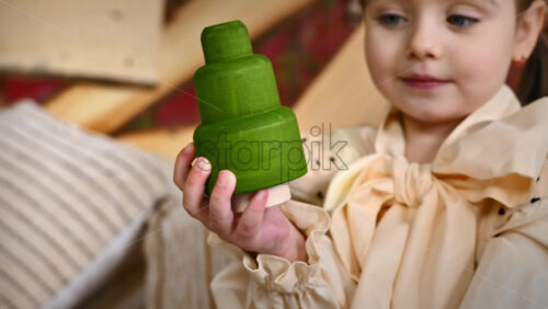 Video - Little girl holding a wooden fir tree toy crafted from linden wood. Ecological and sustainability concept