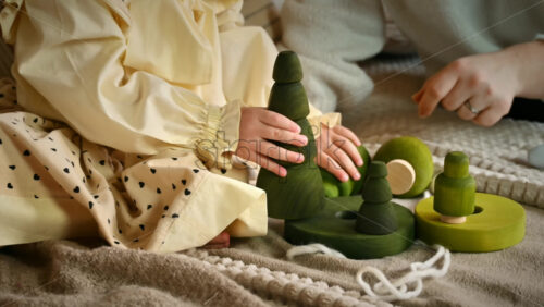 Video - Little girl and her mother playing with several wooden tree toys. Ecological and sustainability concept