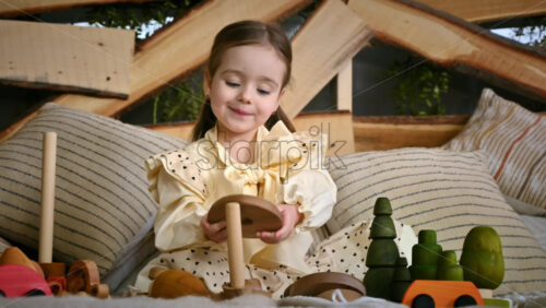 Video - Happy little girl playing with wooden toys and smiles. Ecological and sustainability concept
