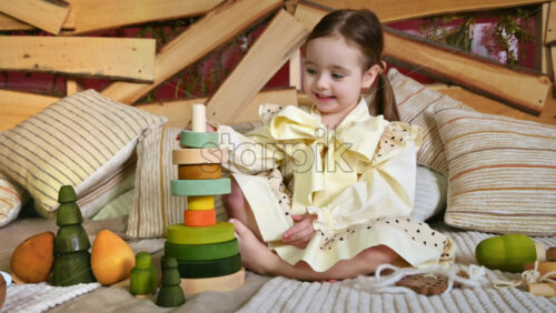 Video - Little girl playing with vibrantly colored blocks of a large wooden pyramid. Ecological and sustainability concept