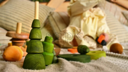 Video - Little girl playing with several wooden toys in background. Green fir toy in foreground. Ecological and sustainability concept