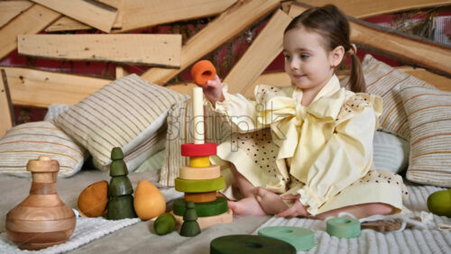 Video - Little girl playing with vibrantly colored blocks of a large wooden pyramid. Ecological and sustainability concept