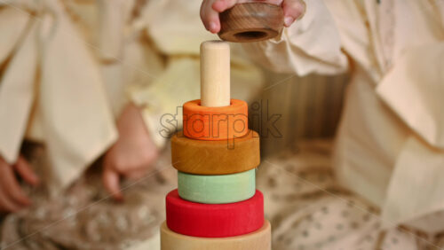 Video - Two little girls playing with vibrantly colored blocks of a large wooden pyramid. Ecological and sustainability concept