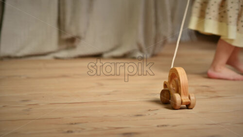 Video - Little girl playing with a wooden snail rolling toy on the floor. Ecological and sustainability concept