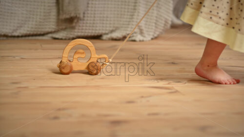 Video - Little girl playing with a wooden snail rolling toy on the floor. Ecological and sustainability concept