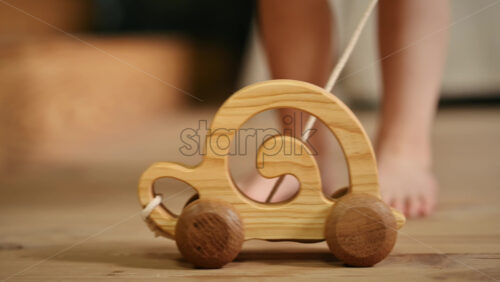 Video - Little girl playing with a wooden snail rolling toy on the floor. Ecological and sustainability concept