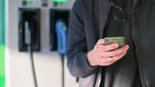 Video - Man using smartphone near an electric car charger