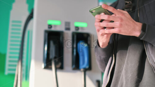 Video - Man using smartphone near an electric car charger