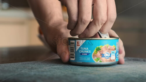 Video - CHISINAU, MOLDOVA - JANUARY 6, 2020: A man opening a can with tuna chunks on a kitchen table