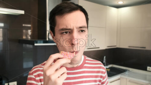 Video - A man eating a rose donut on the kitchen