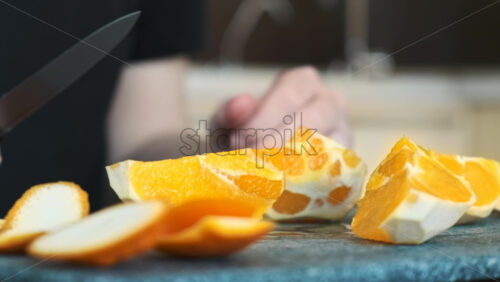 Video - A man slicing an orange on a cooking board using a knife