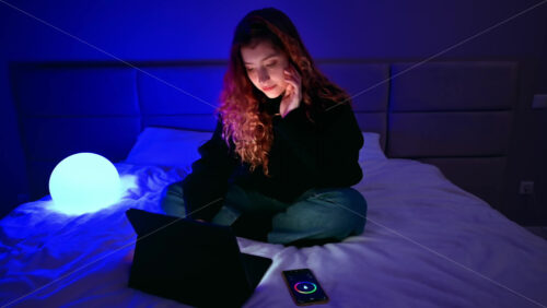 Video - Young ginger hair girl using her tablet in the bedroom with smart lamp on background. Changing hue color. Smart home