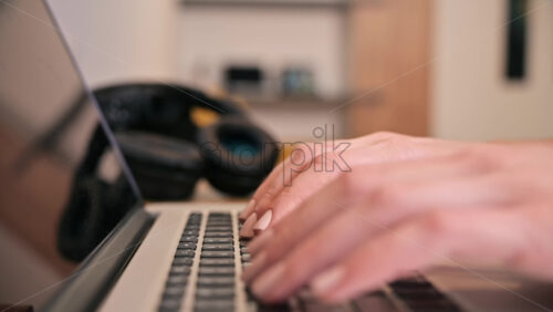 Video - Female hands typing on laptop with headphones on background. Working from home