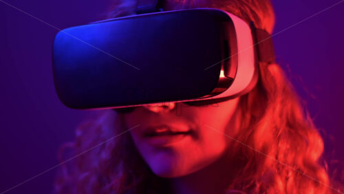 Video - Young ginger hair girl using virtual reality headset with colorful neon lights