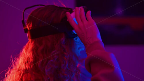 Video - Young ginger hair girl using virtual reality headset with colorful neon lights