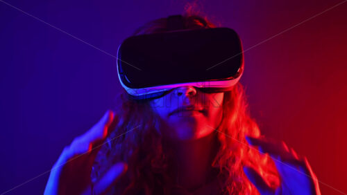Video - Young ginger hair girl using virtual reality headset with colorful neon lights