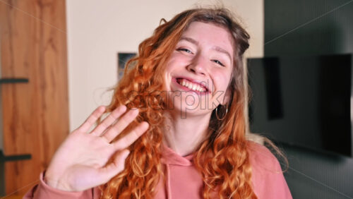 Video - Portrait of young girl with ginger hair waving hand. Working from home