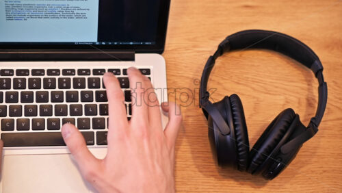 Video - Top view of man hands taking headphones from the table. Working from home on laptop