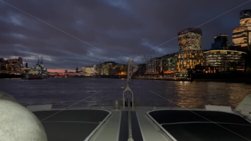 Video - The flag of the United Kingdom waving on a boat moving on the Thames River in the evening in London, England