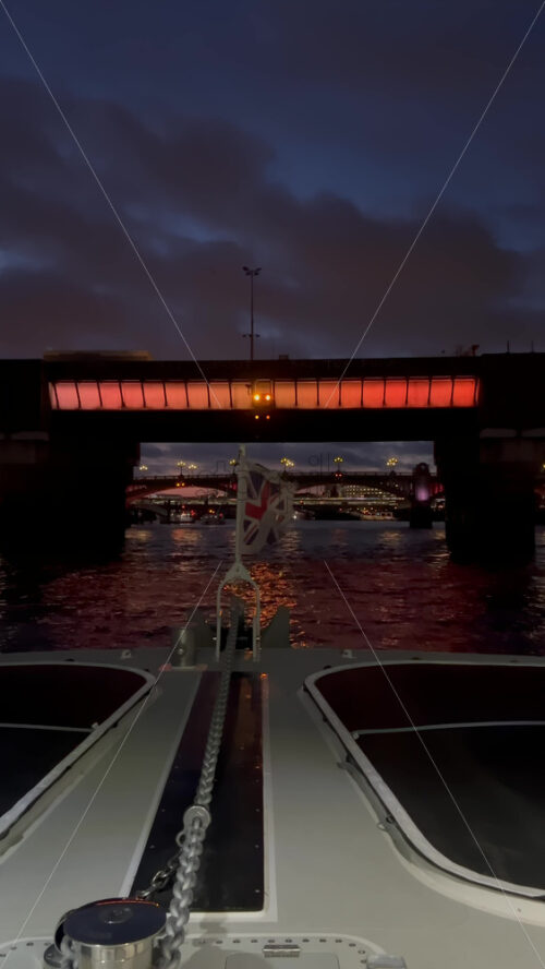 Video - The flag of the United Kingdom waving on a boat moving on the Thames River in the evening in London, England. Vertical