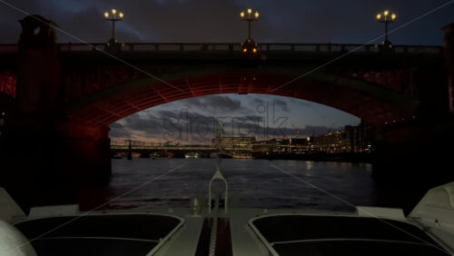 Video - The flag of the United Kingdom waving on a boat moving on the Thames River in the evening in London, England