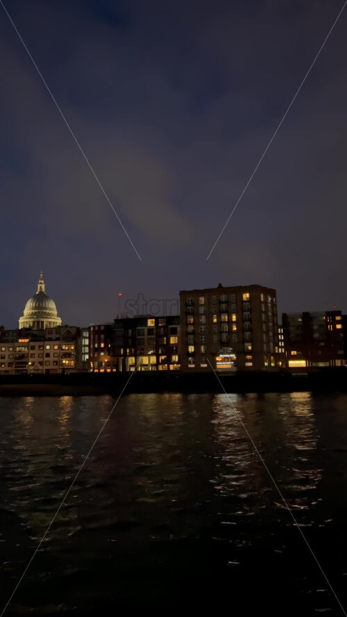 Video - View from a moving boat of the buildings alongside the Thames River in the evening in London, England. Vertical